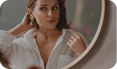 Woman adjusting hair in front of a mirror.