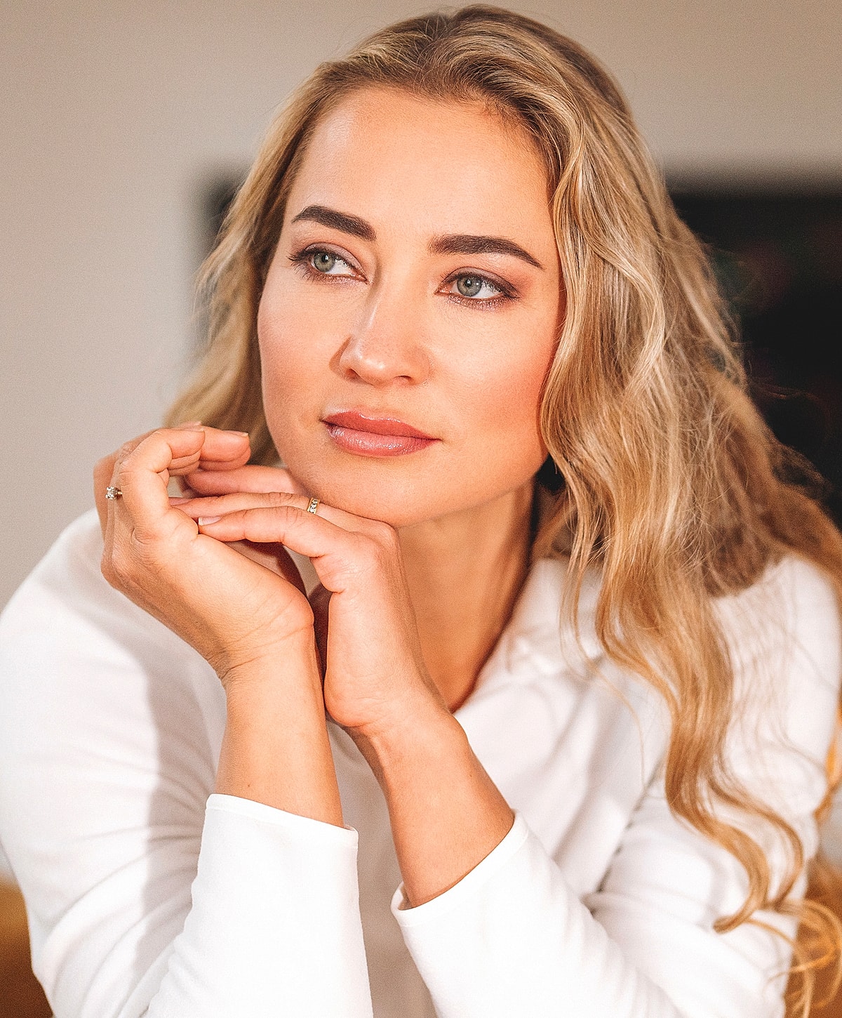 Thoughtful woman with long, wavy blonde hair.