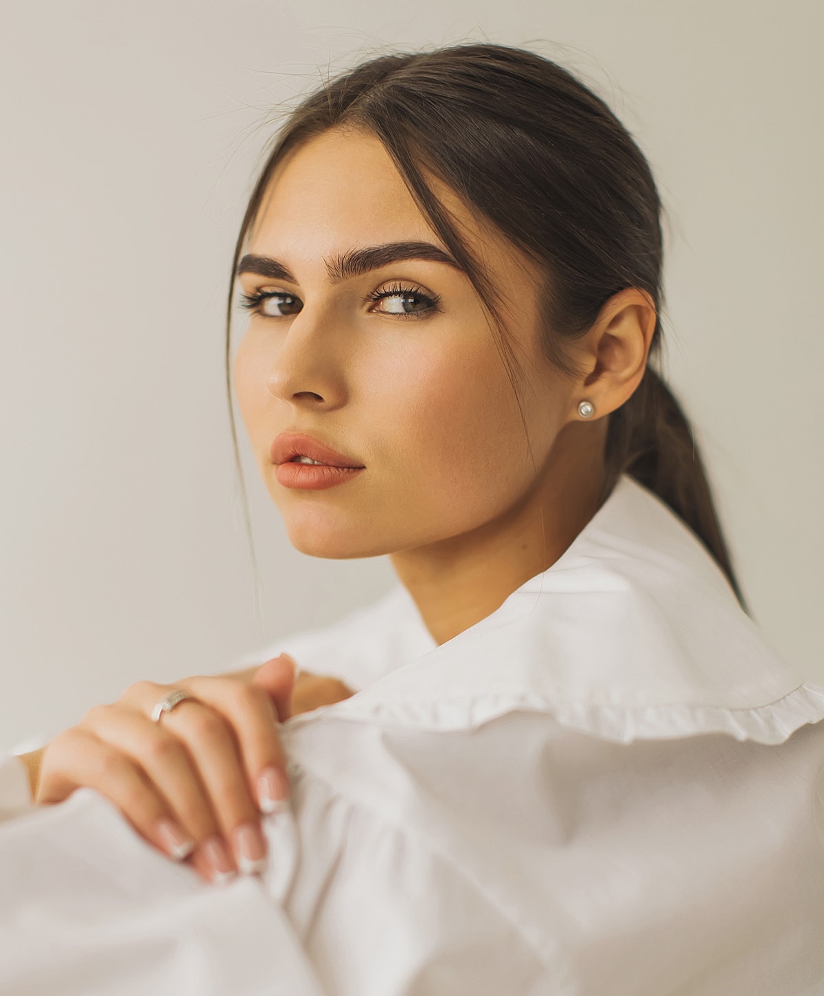 Woman in white shirt, natural makeup, thoughtful expression.