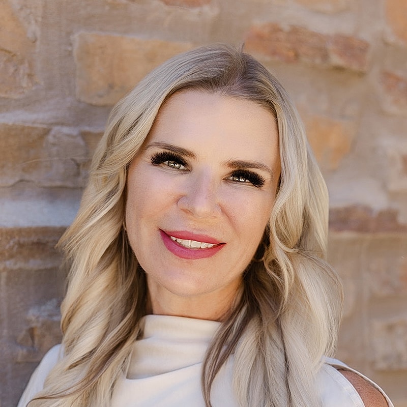 Smiling woman with long blonde hair, neutral background.