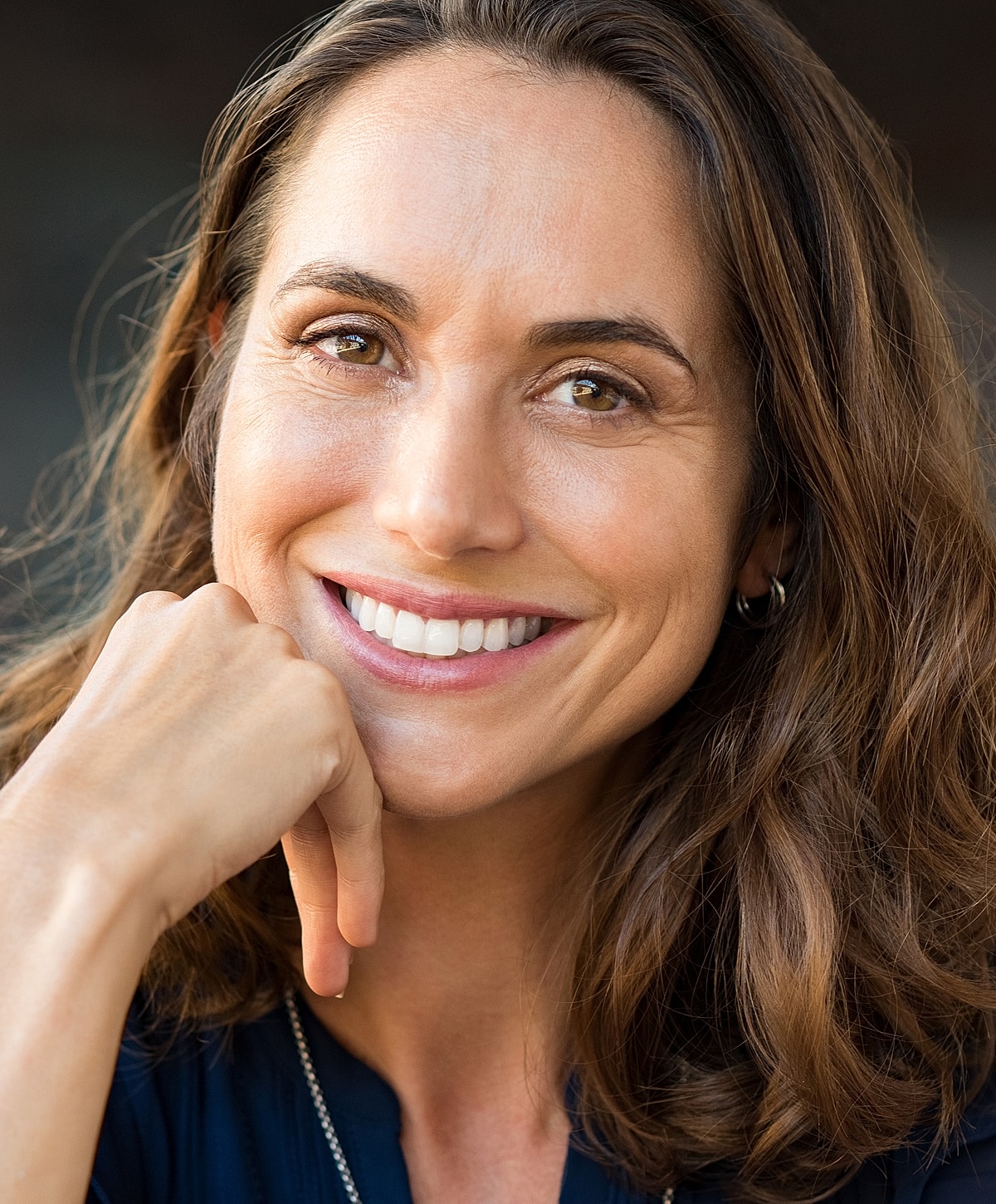 Smiling woman resting chin on hand.