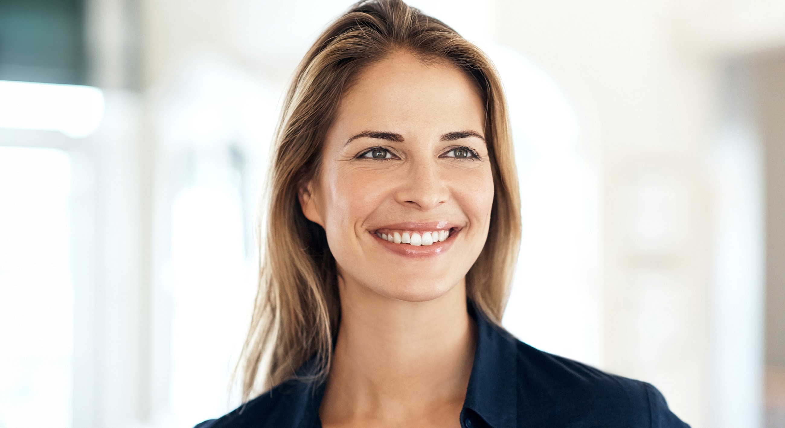 Smiling woman with long hair in indoor setting.