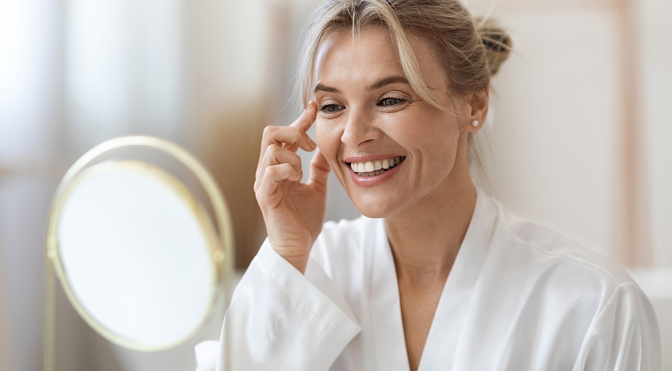 Woman applying skincare in front of mirror.